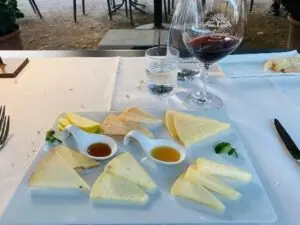 Plankje pecorino met honing en een glas rode wijn op tafel