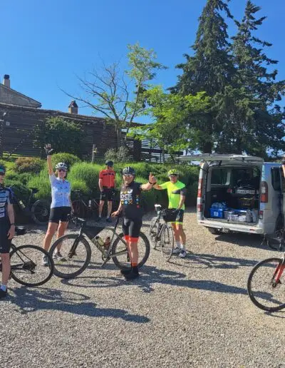 Fietsers verzamelen bij de volgwagen op een grindplein voor de start