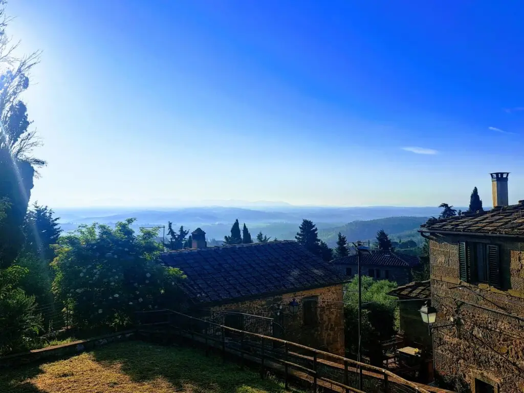 Ochtendlicht boven een Toscaans heuveldorp met stenen huizen en mistig dal