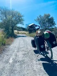 Bepakte reisfiets met tassen stilstaand op een witte grindweg