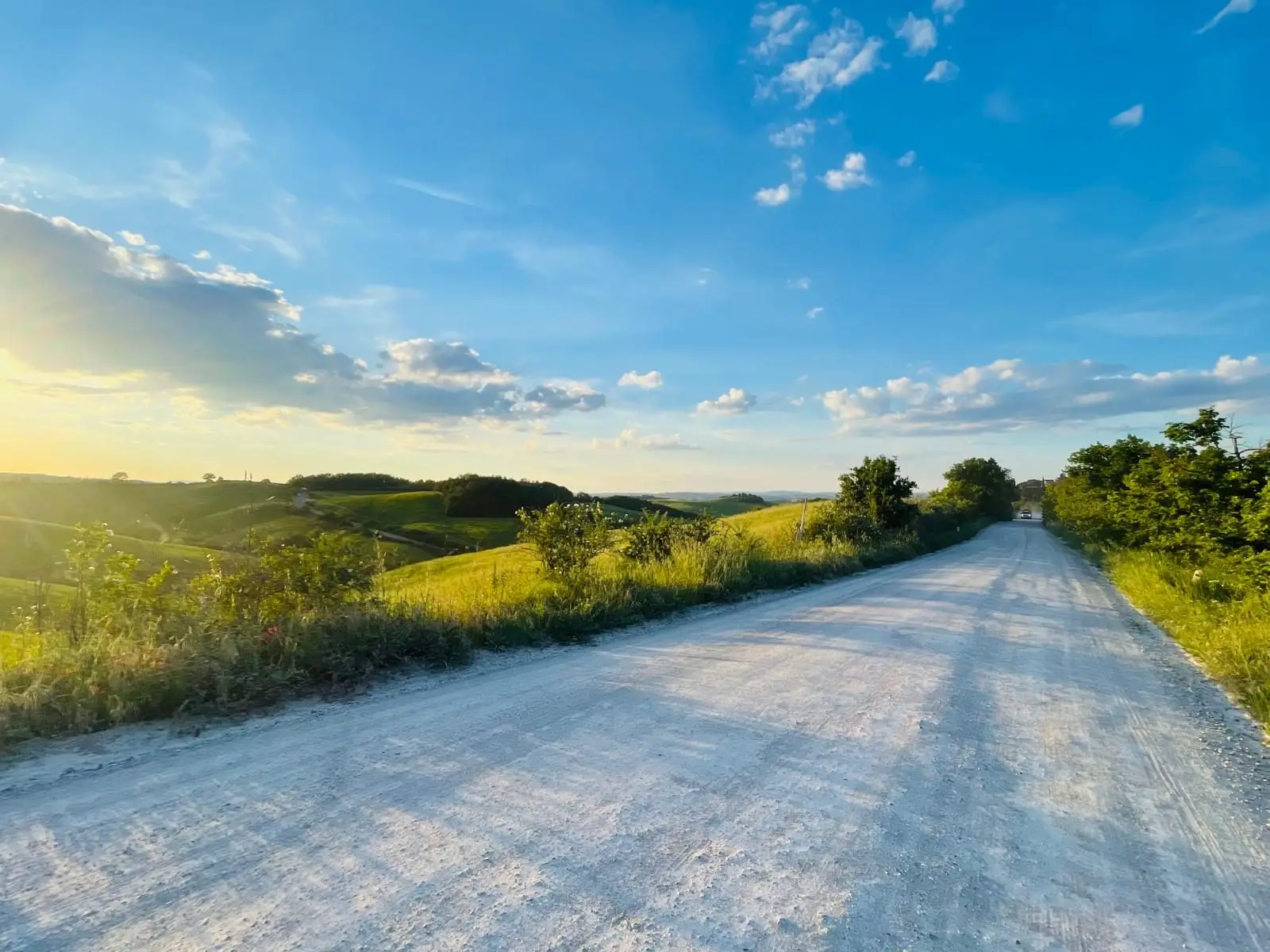 Witte grindweg, een strada bianca, door groene Toscaanse heuvels in avondlicht