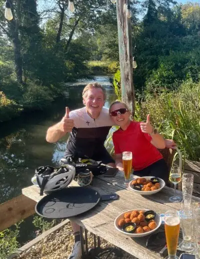 Fietsers met duim omhoog aan een tafel met bier en bitterballen