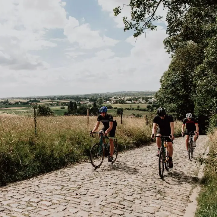 Drie fietsers klimmen over de kasseien van de Koppenberg in Vlaanderen