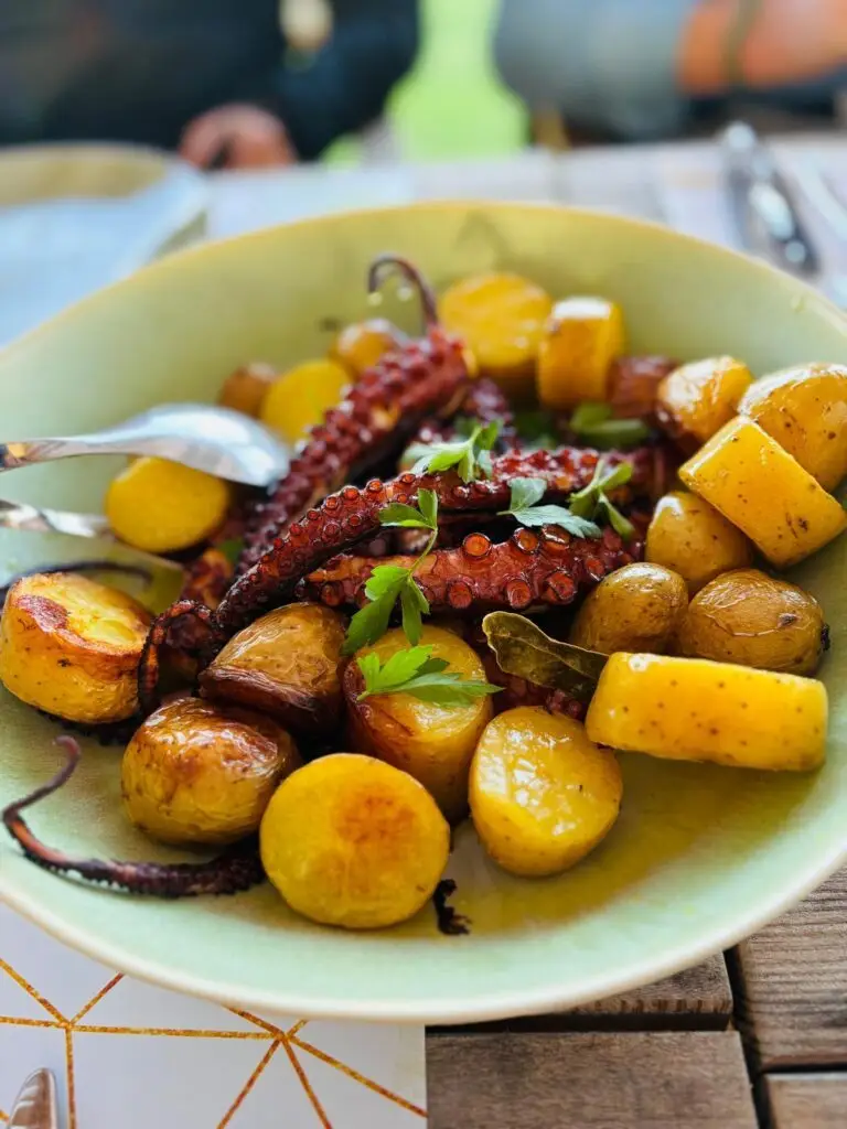 Kom met gegrilde octopus, krieltjes en peterselie op een groen bord
