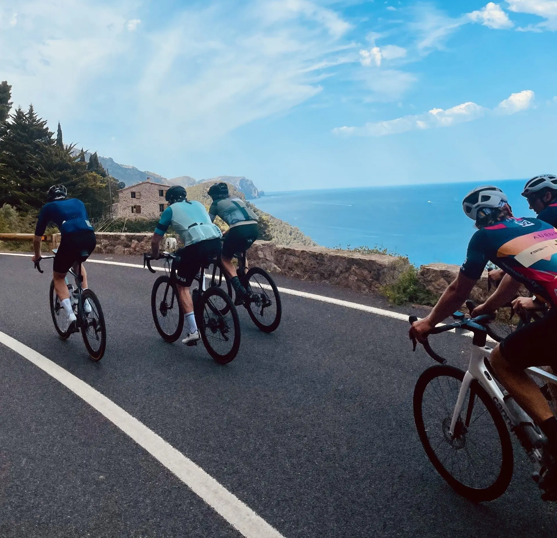 Vier fietsers op de kustweg langs de blauwe zee op Mallorca